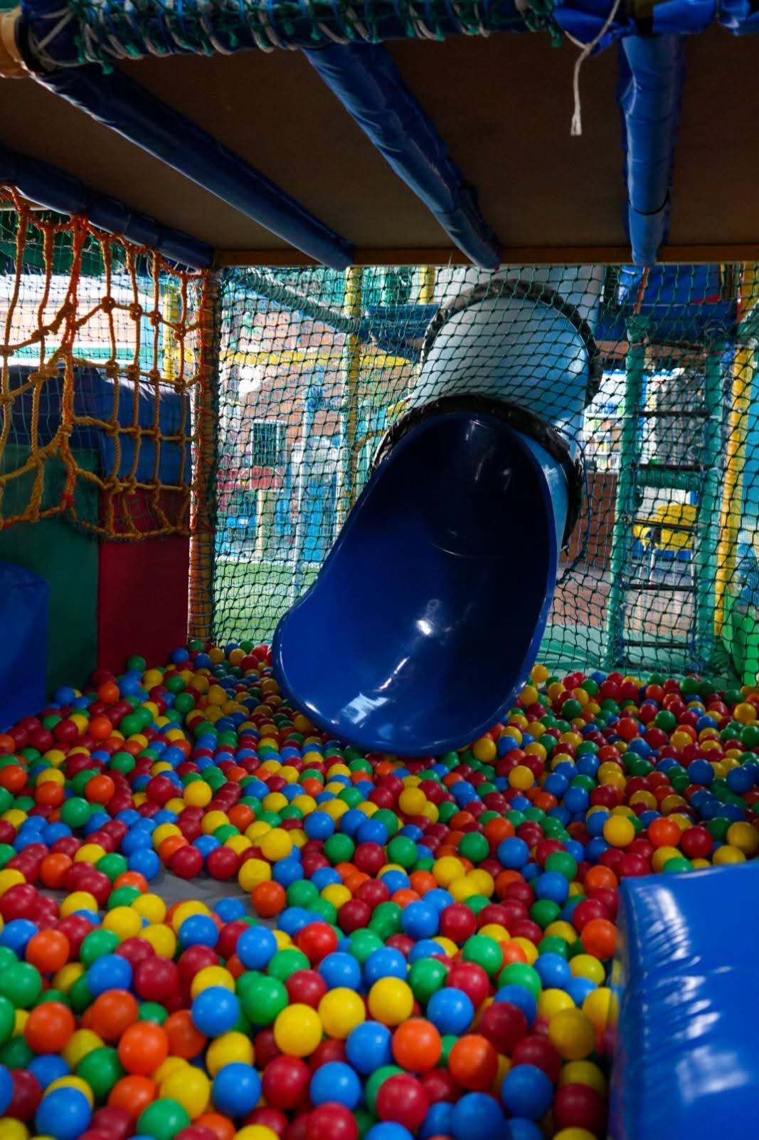 Blue tube slide into colourful ball pit